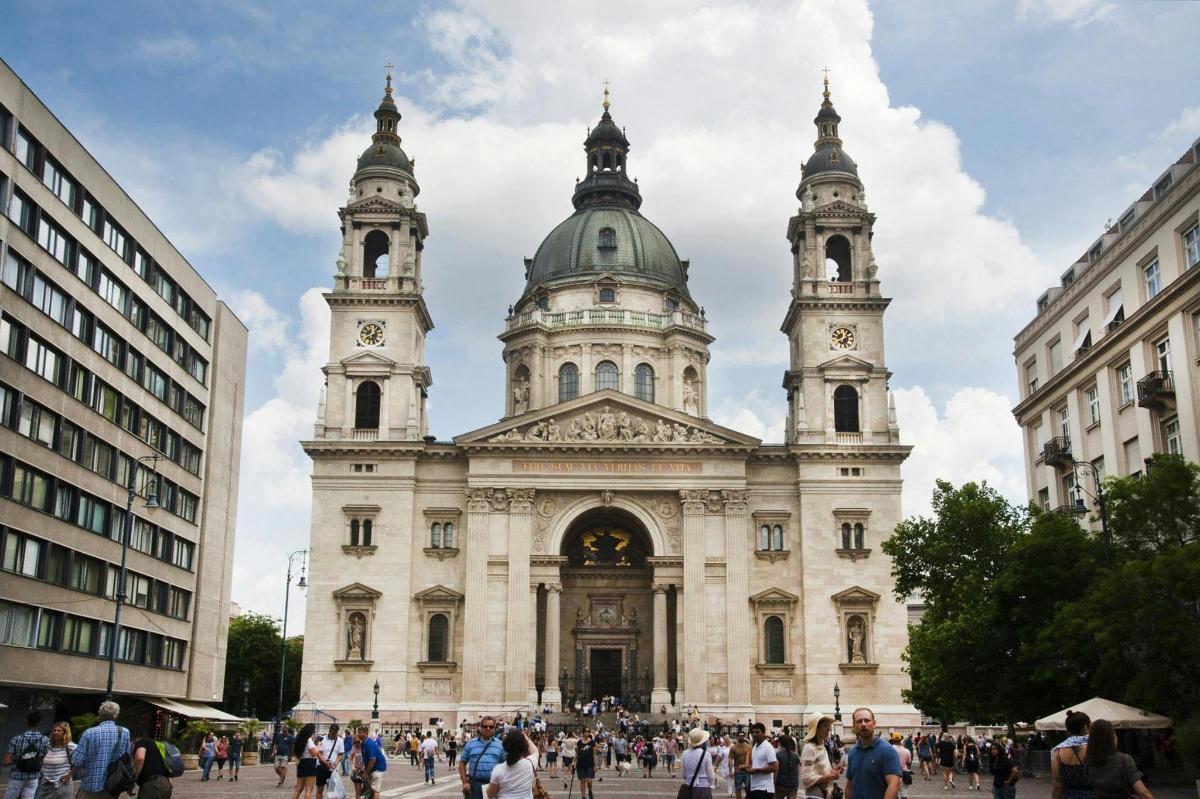 a building with two towers with people walking in front