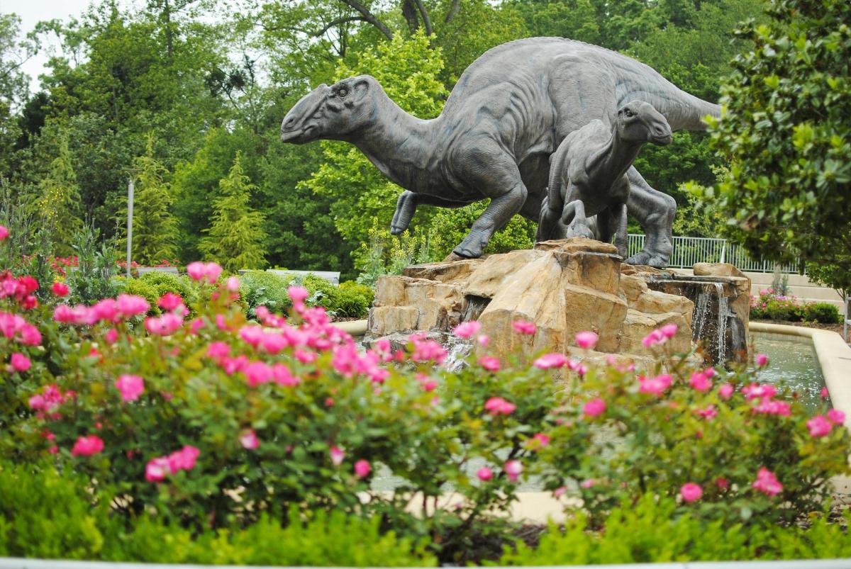 a statue of two sheep on a rock with pink flowers