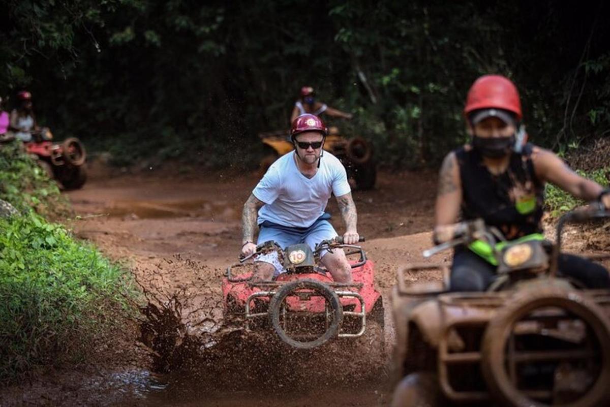 two people riding on atvs on a dirt road