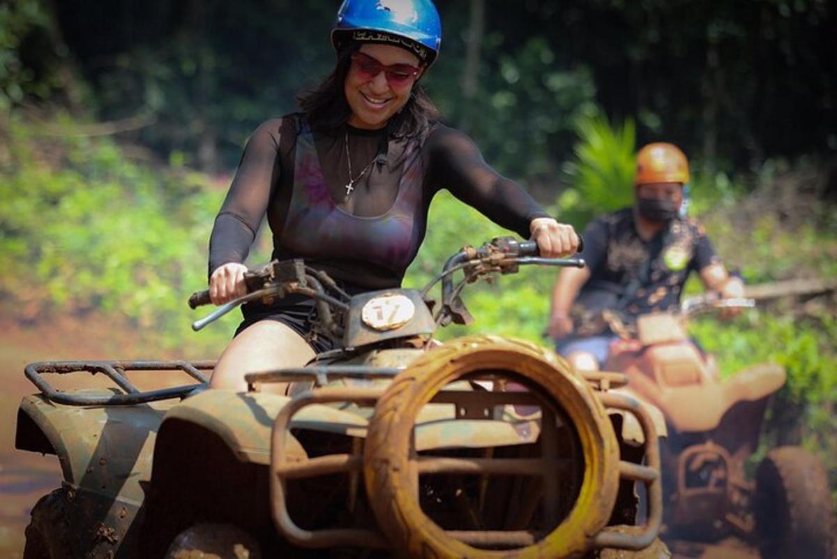 two people riding on atvs down a dirt road