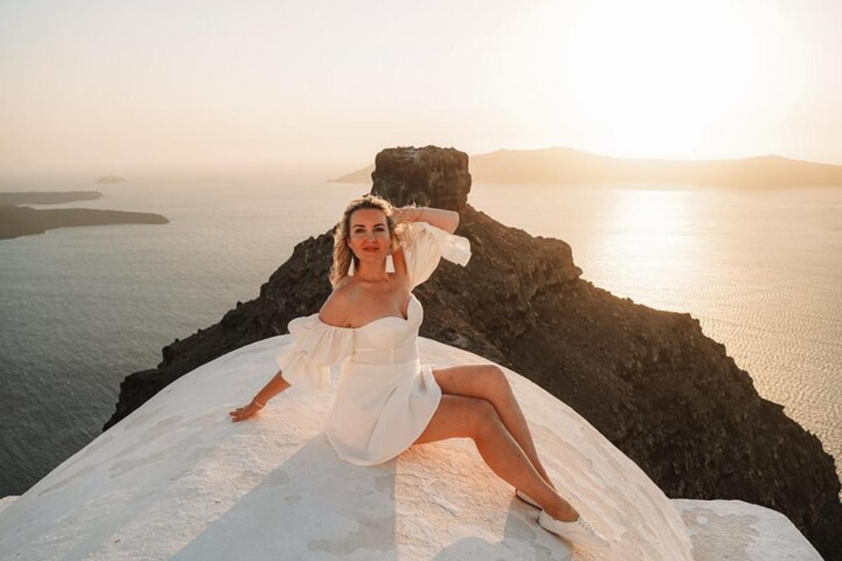 Una mujer con un vestido blanco sentada en una roca cerca del océano.