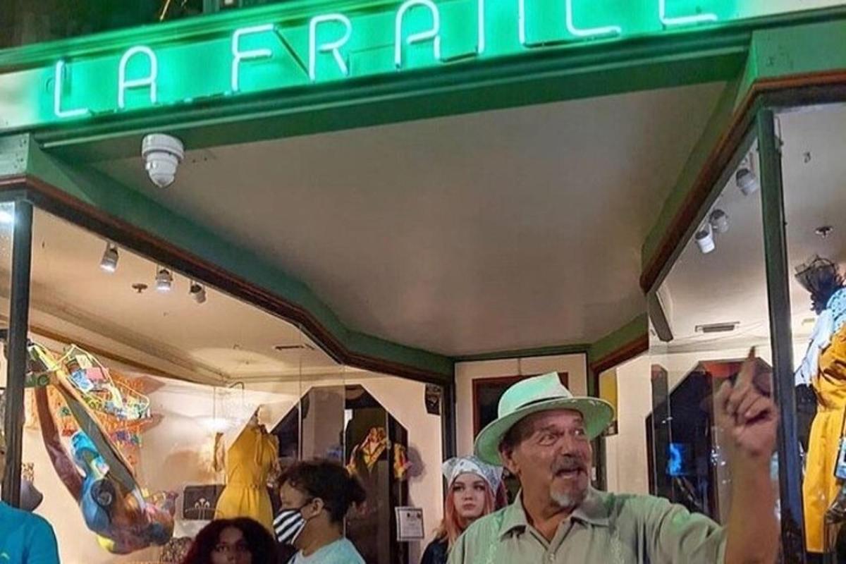 Un hombre con sombrero parado frente a una tienda.