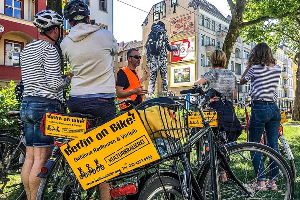 een groep mensen die naast fietsen staan met een bord
