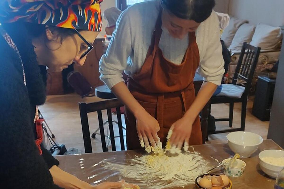 to kvinder står omkring et bord og tilbereder mad