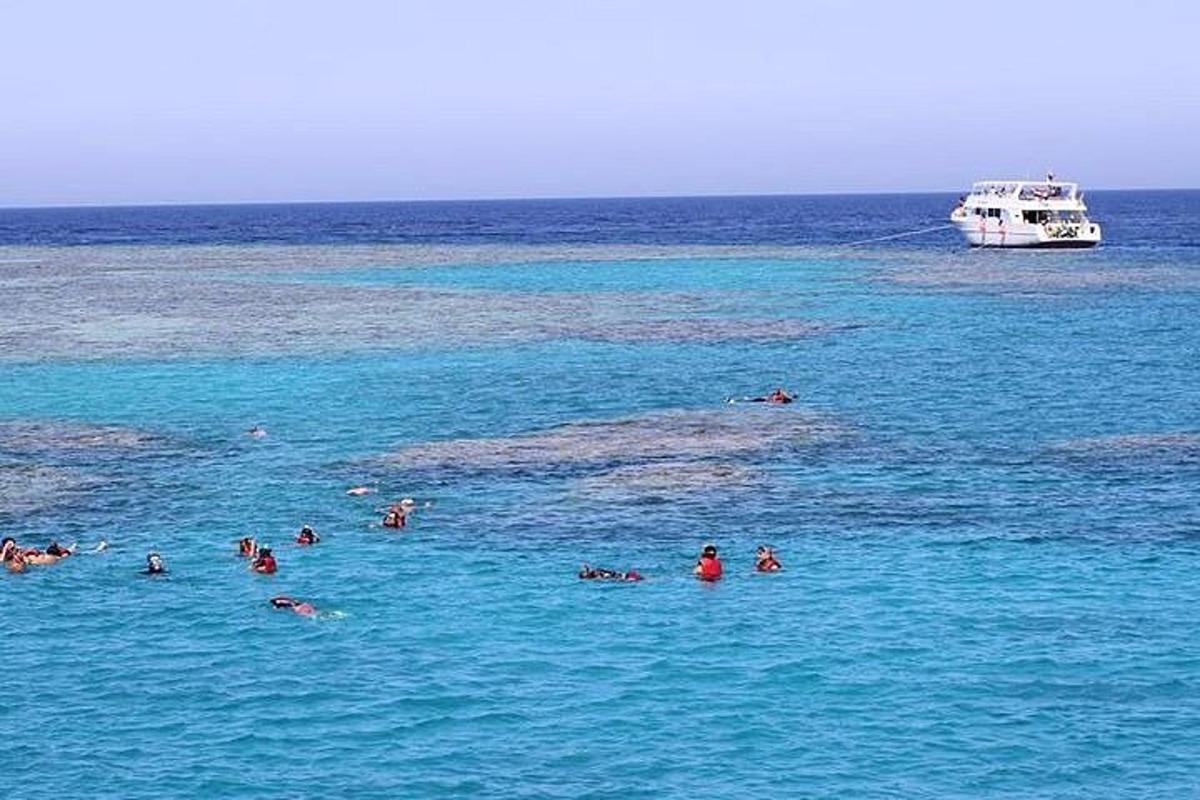 Un grupo de personas nadando en el océano con un bote.