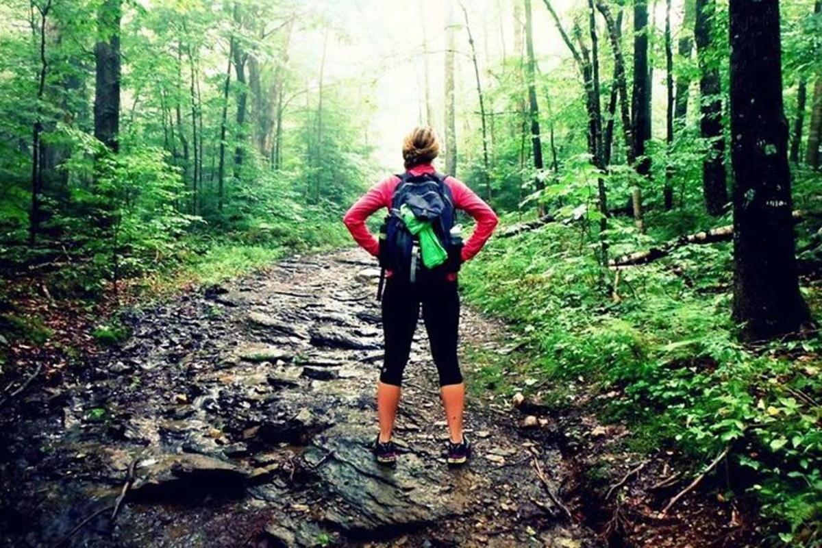 a woman with a backpack standing on a forest trail