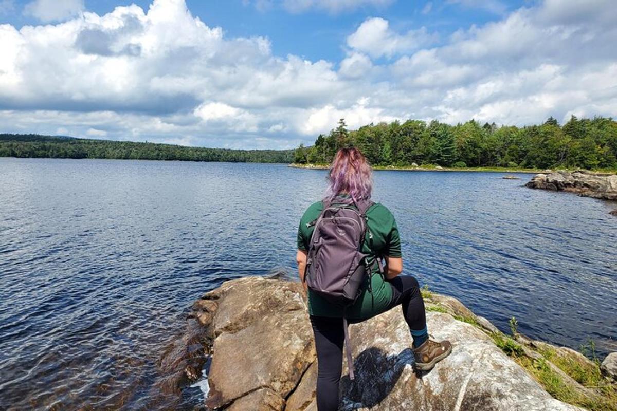 a person sitting on a rock by a lake