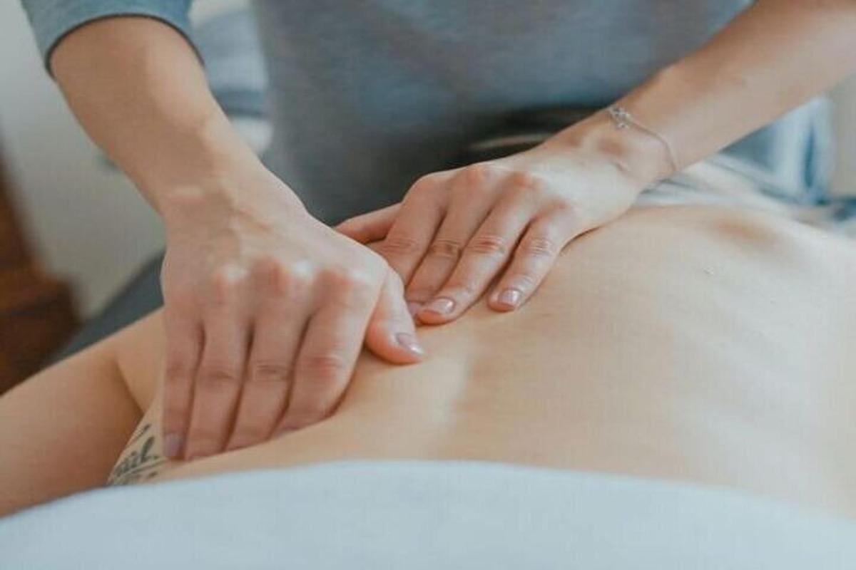 uma mulher recebendo uma massagem nas costas de um terapeuta