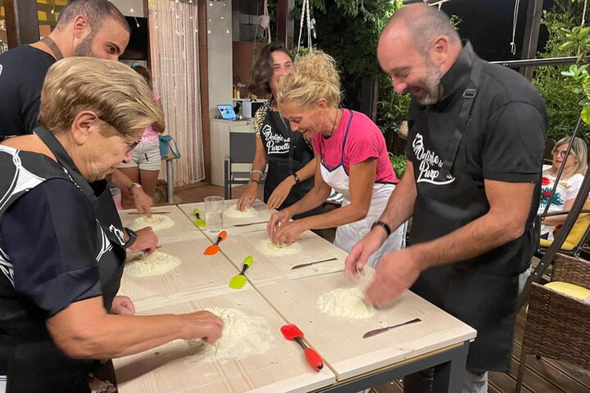 um grupo de pessoas em pé ao redor de uma mesa fazendo bolos