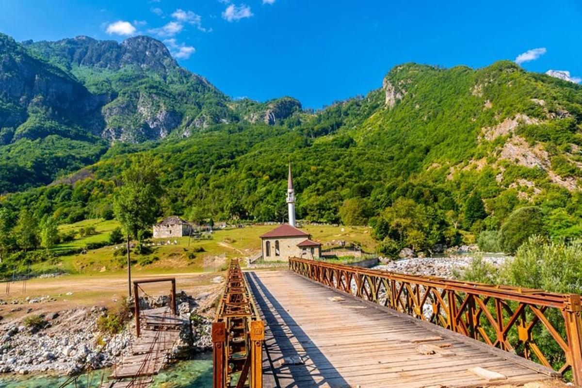 uma ponte sobre um rio com uma igreja e montanhas