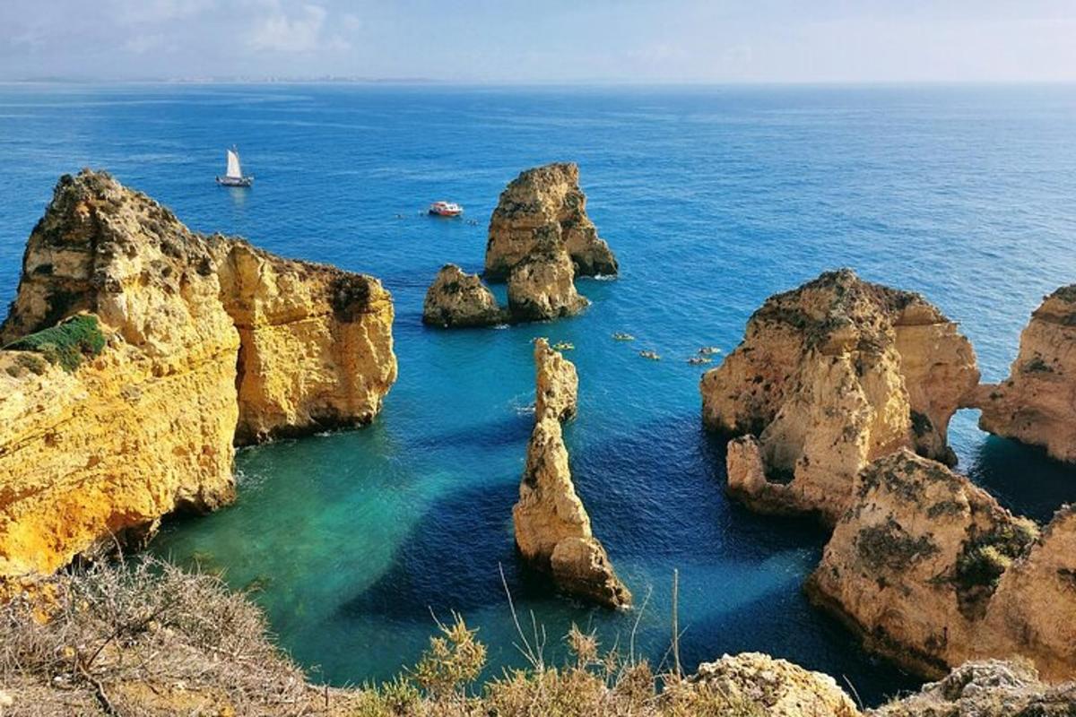 un grup de roci în ocean cu o barcă cu pânze