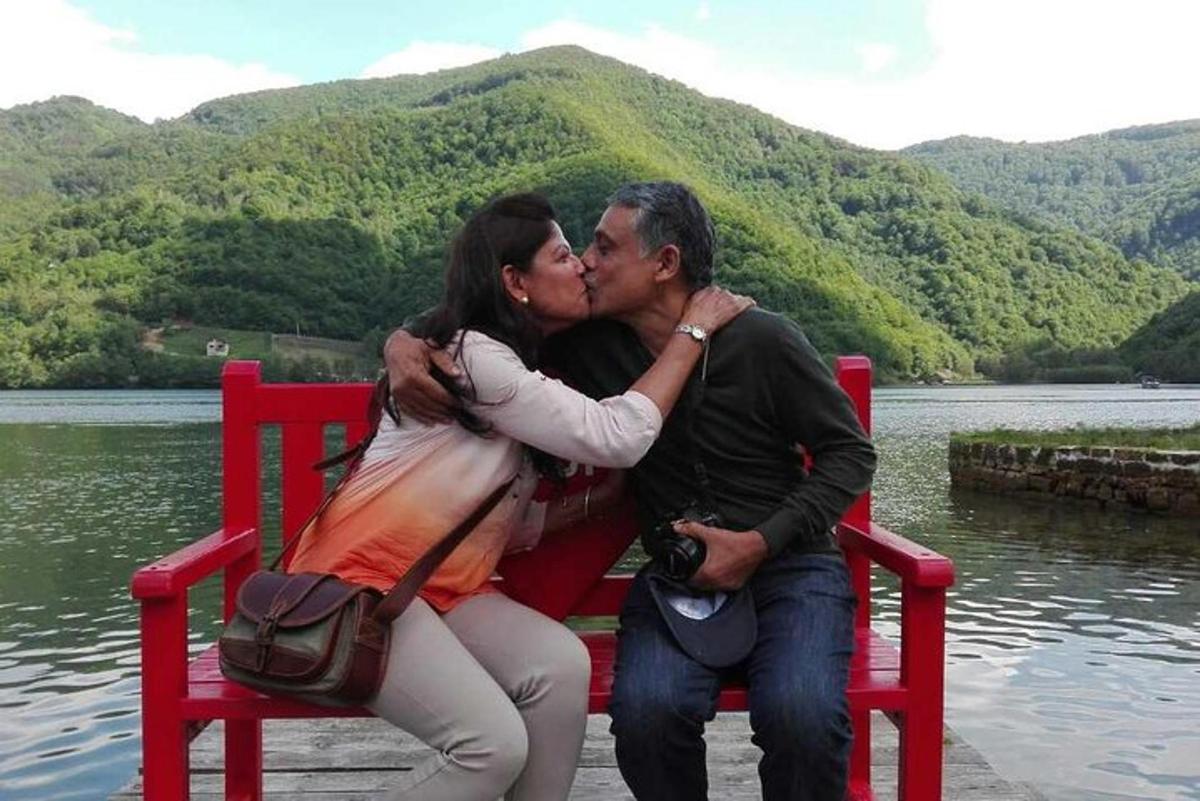 a man and woman sitting on a red bench kissing