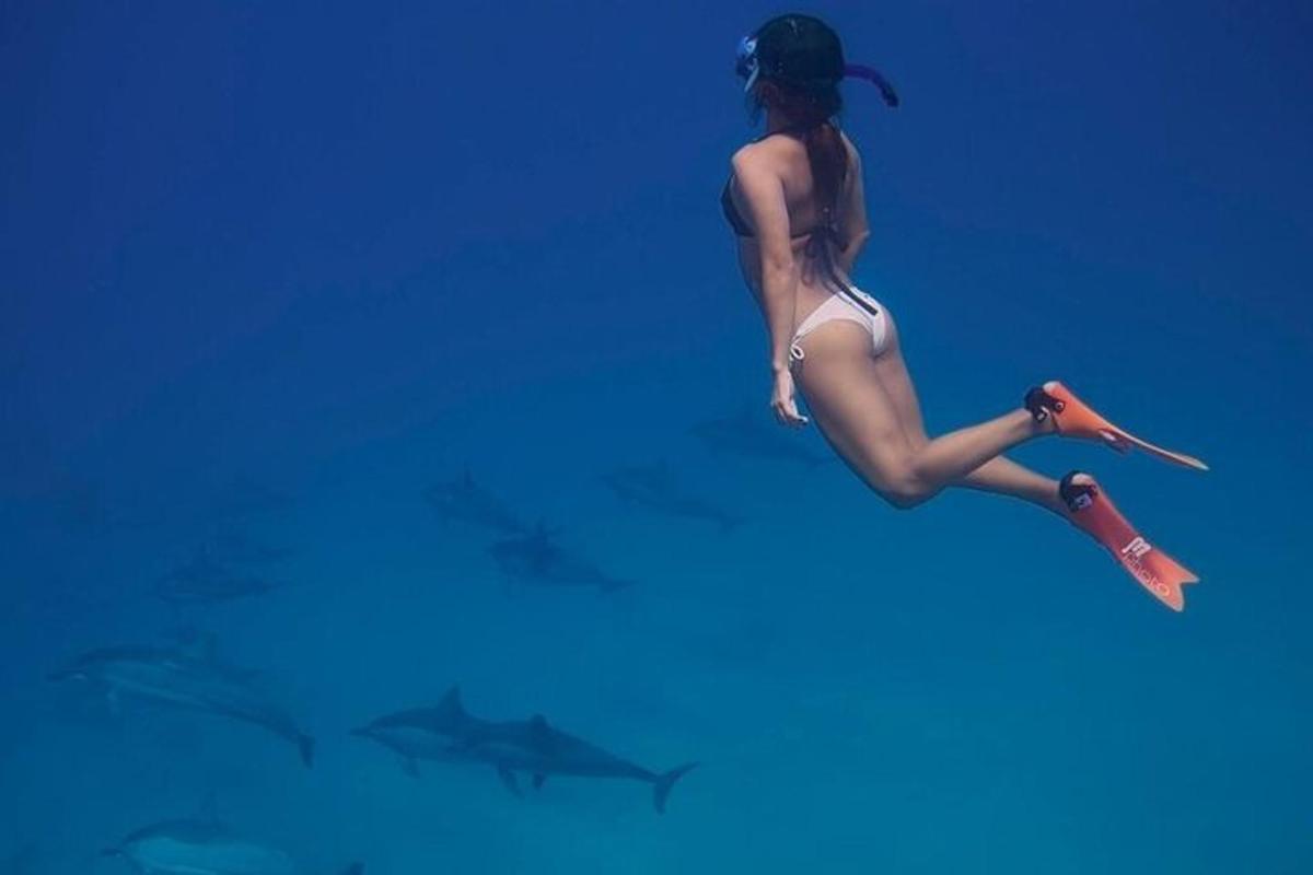 Una mujer en bikini flotando en el agua con tiburones.
