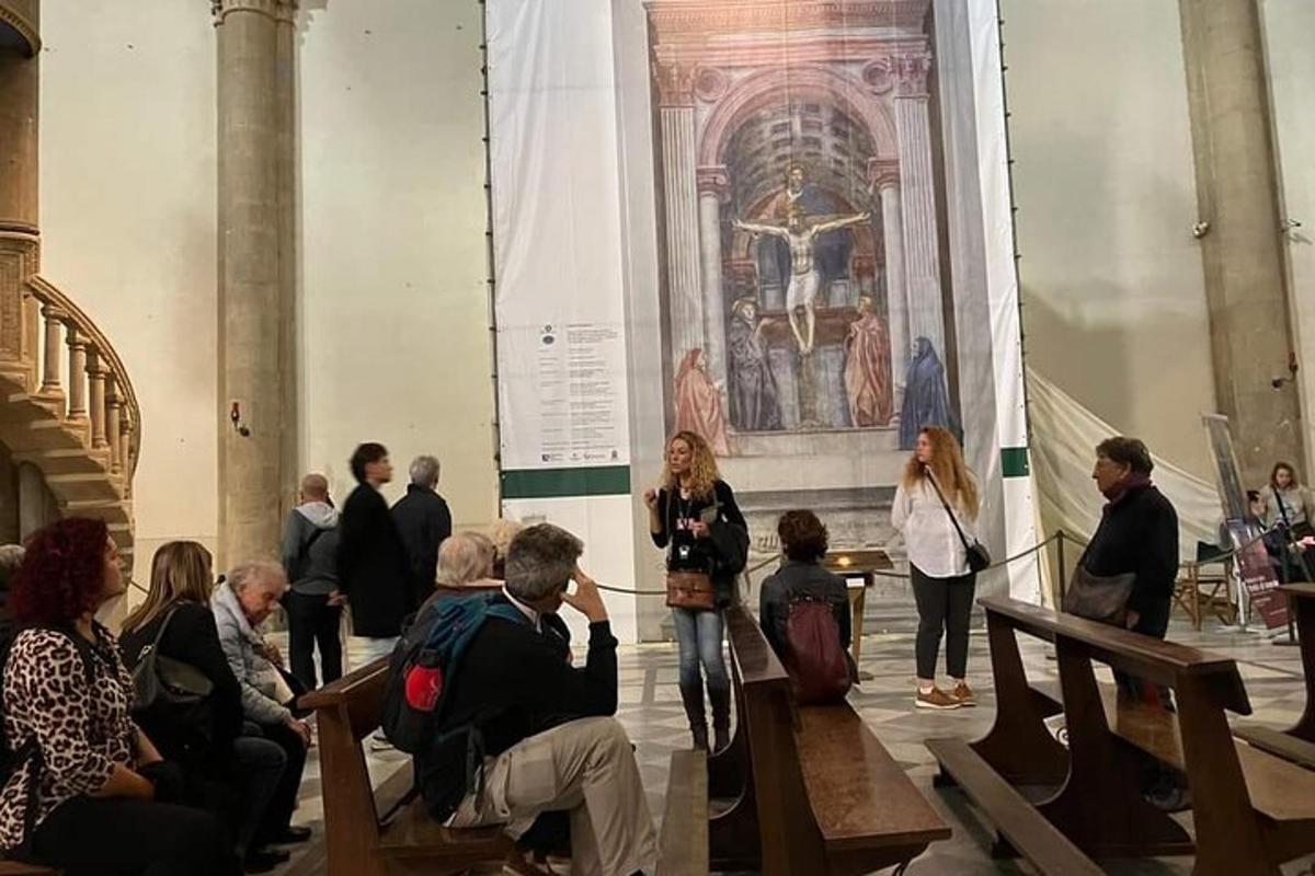 grupė žmonių dideliame kambaryje su paveikslu