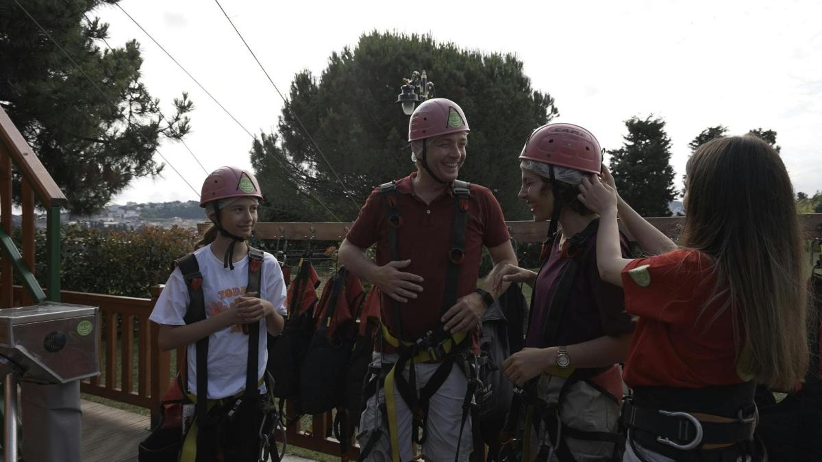a group of people wearing helmets on a zip line