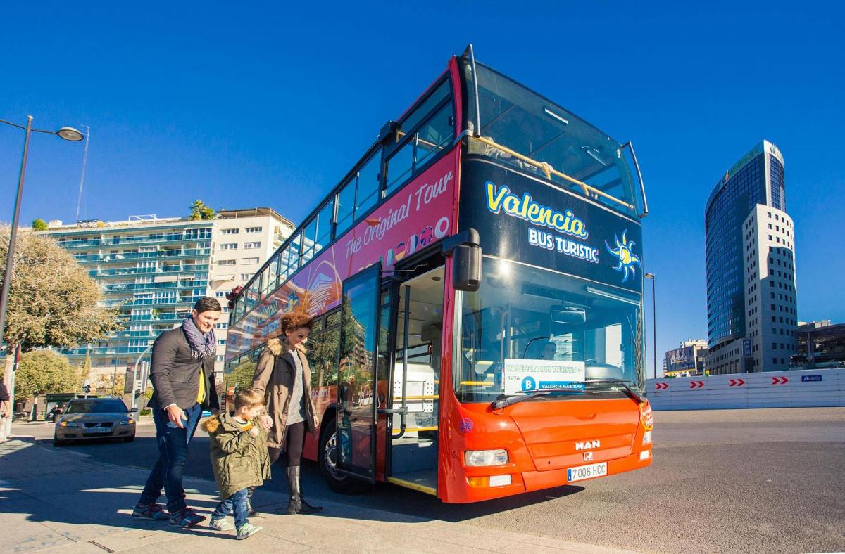 un grup de persones dretes davant d'un autobús de dos pisos