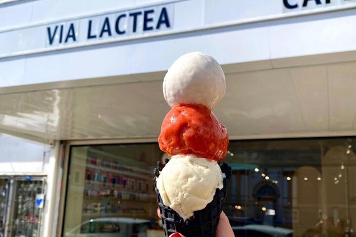 a person holding up a ice cream cone in front of a store