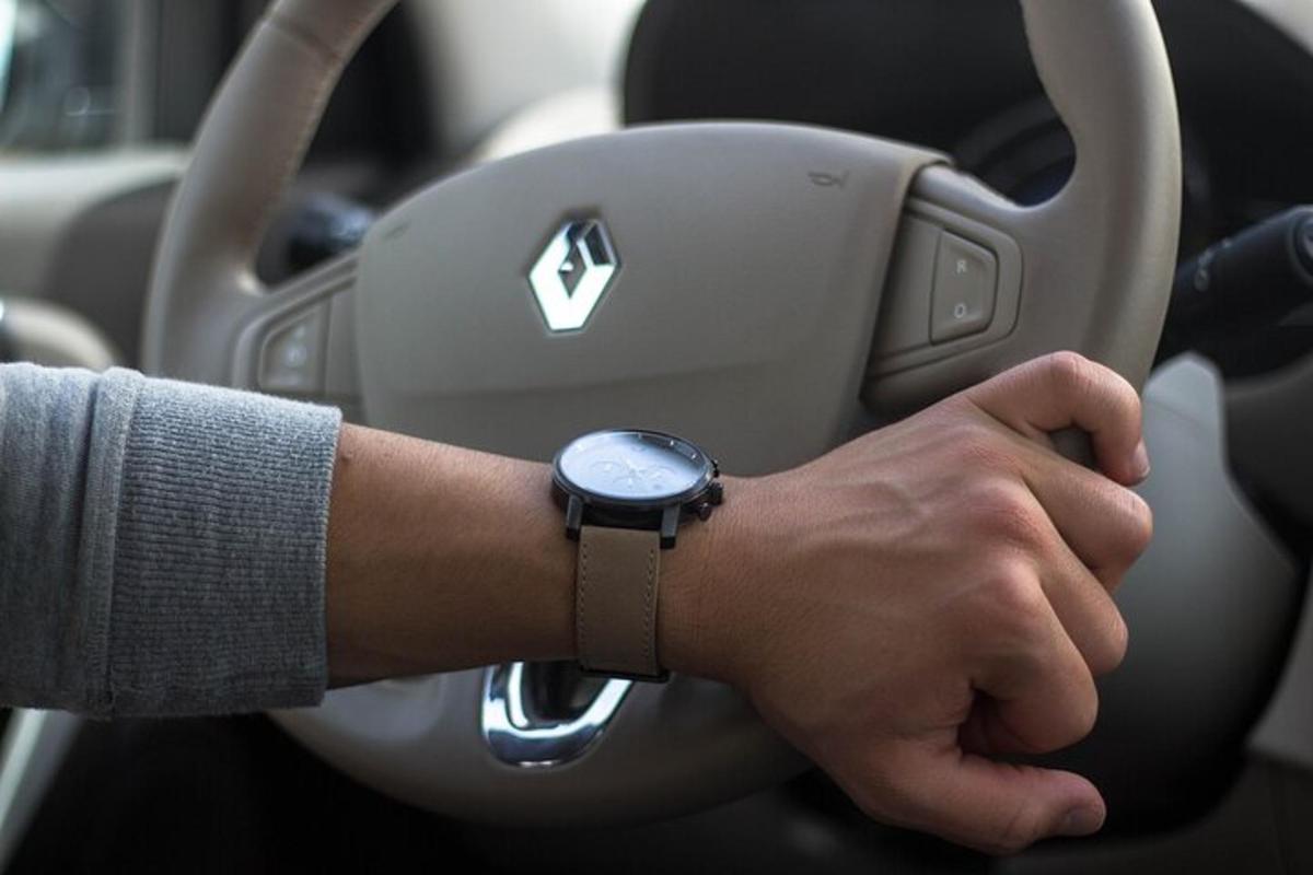 seorang lelaki memandu kereta dengan jam tangan di lengannya