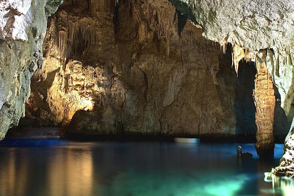 a cave with blue water in front of a cliff