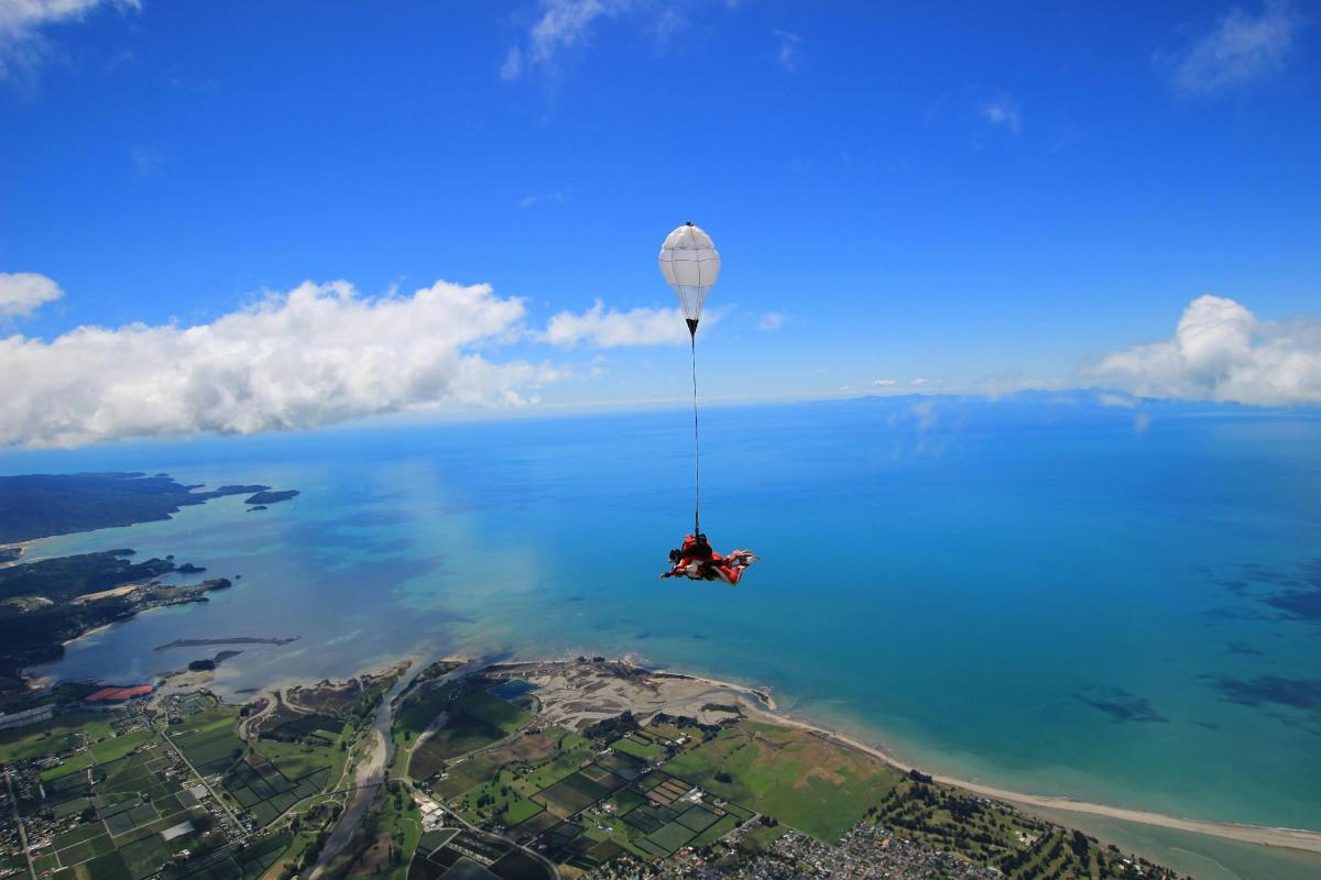 a person is hanging from a hot air balloon over the water