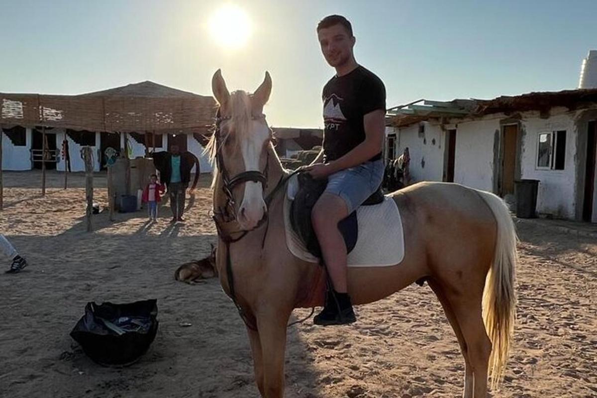 un uomo seduto a cavallo sulla spiaggia