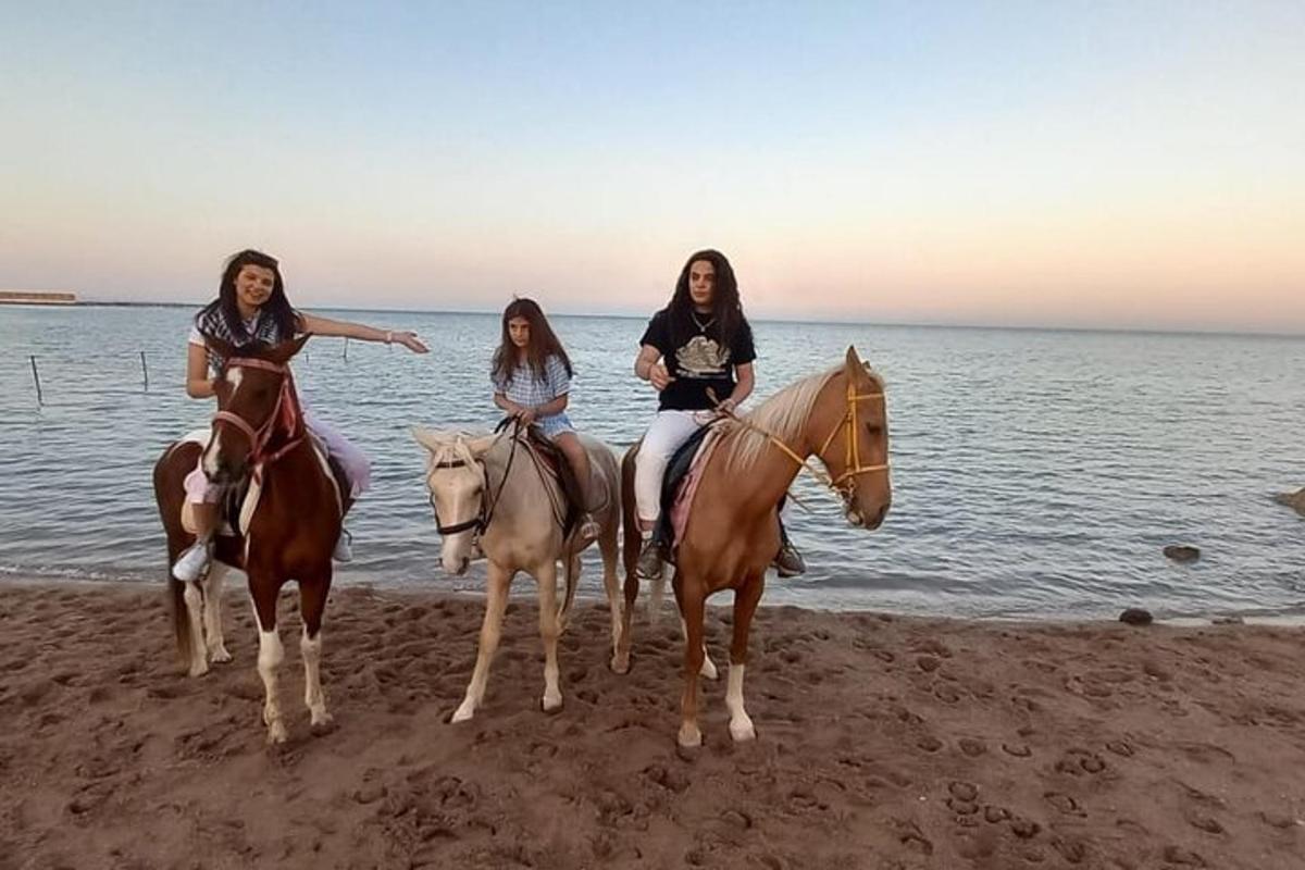 tri ženske jahajo konje na plaži