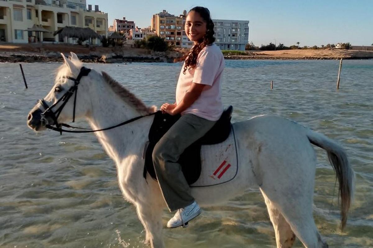 en kvinde, der rider på en hvid hest i vandet