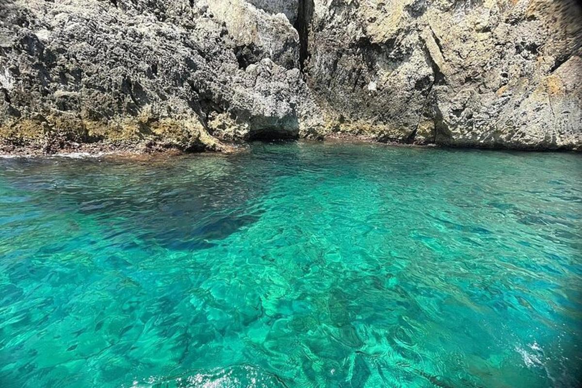 a pool of clear blue water next to a cliff