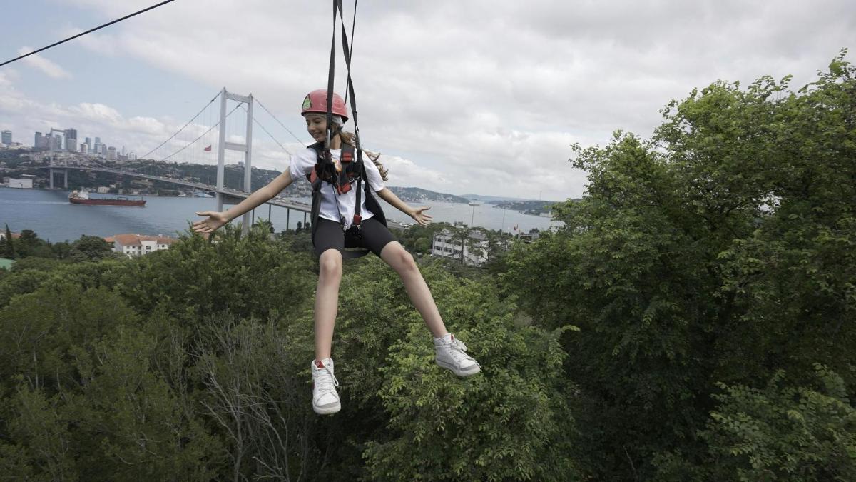 a girl is on a zip line on a hill