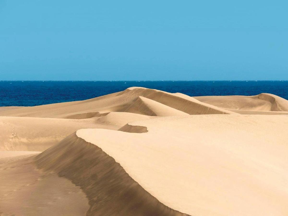 a sand dune with the ocean in the background