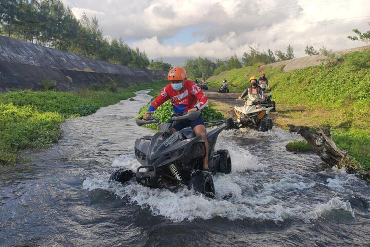 a man riding a four wheeler crossing a river