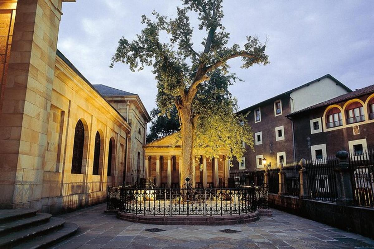a tree in front of a building with a fence