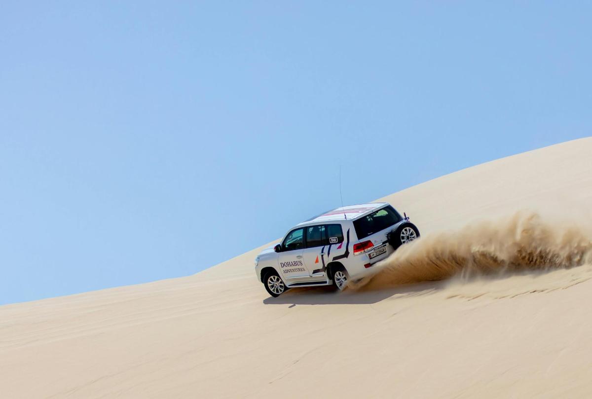 ein weißer Lastwagen, der eine Sanddüne hinunterfährt
