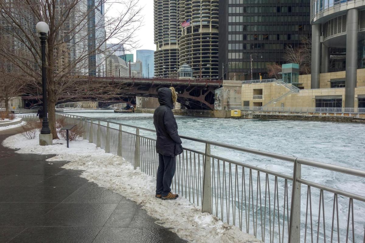 a man standing next to a fence next to a river