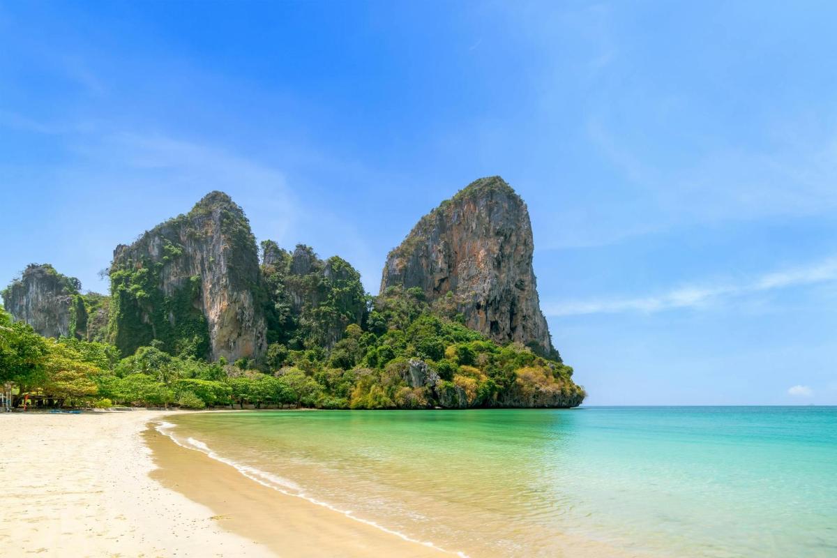 a beach with rocks in the water and a beach with sand and trees