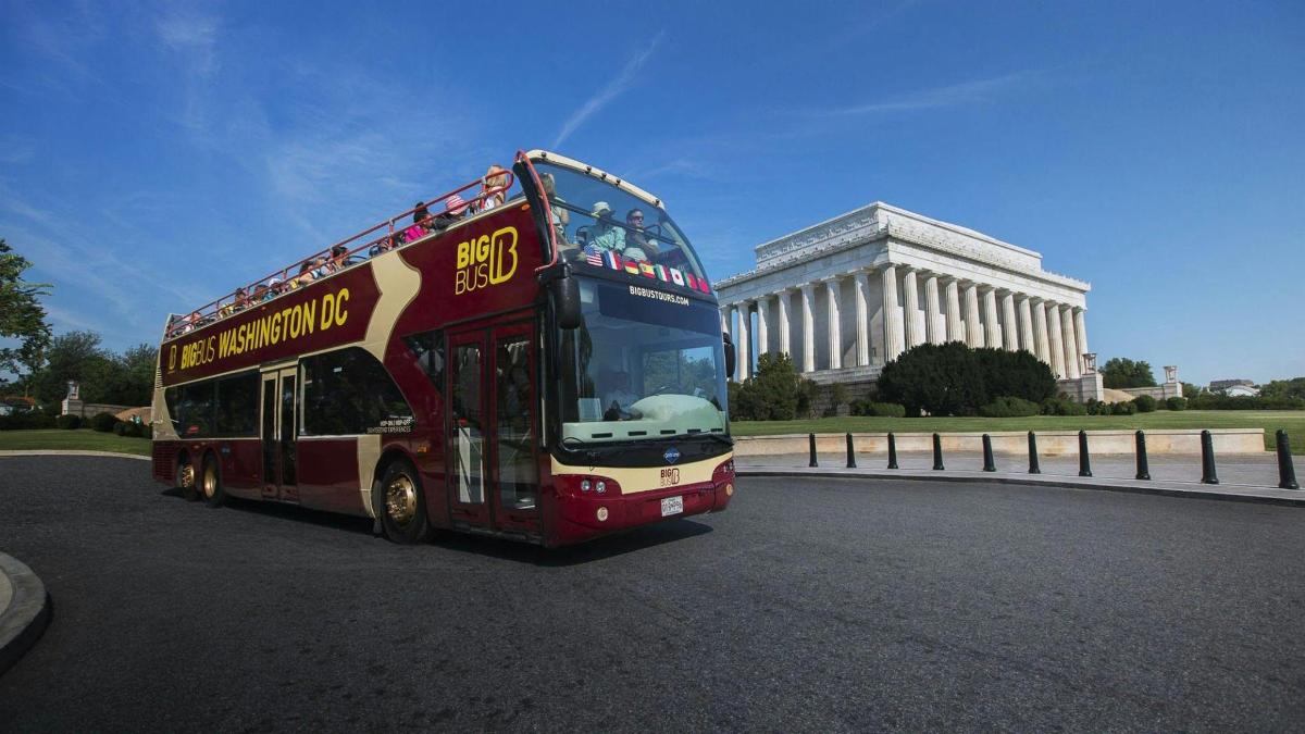egy piros emeletes busz elhajt egy épület mellett