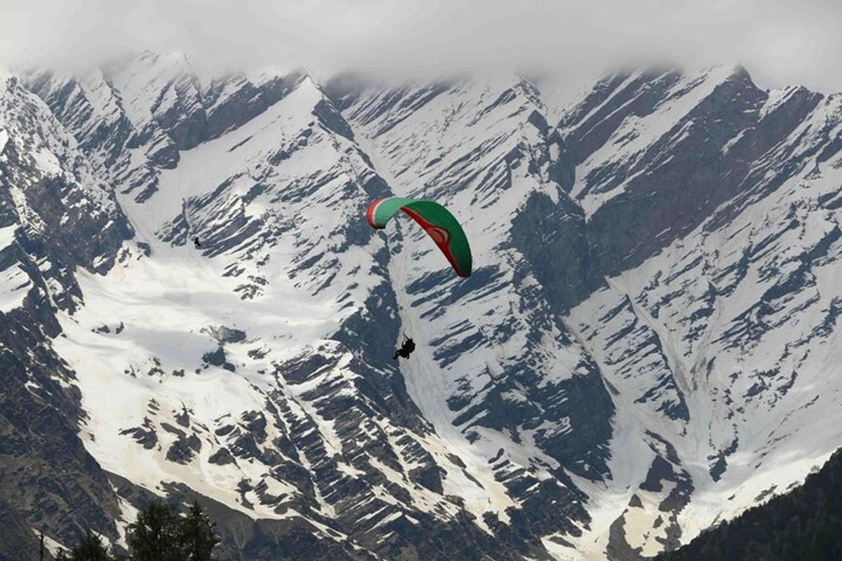 a person flying a kite over a snow covered mountain