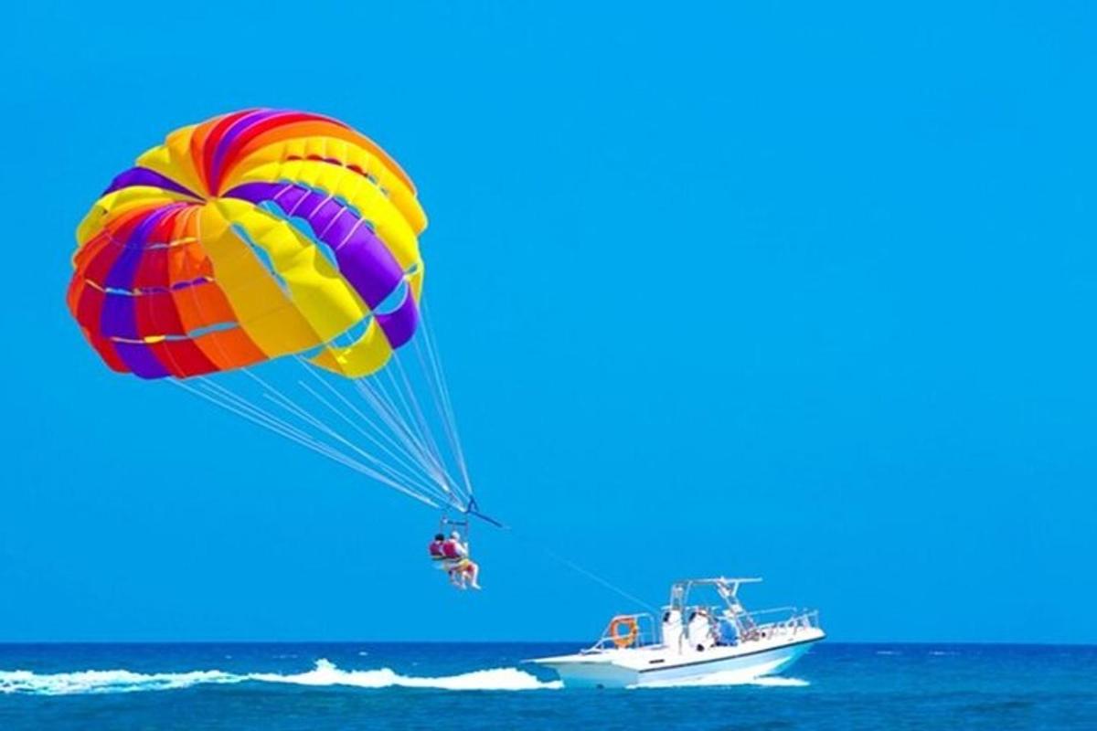 um grande paraquedas colorido voando sobre um barco no oceano
