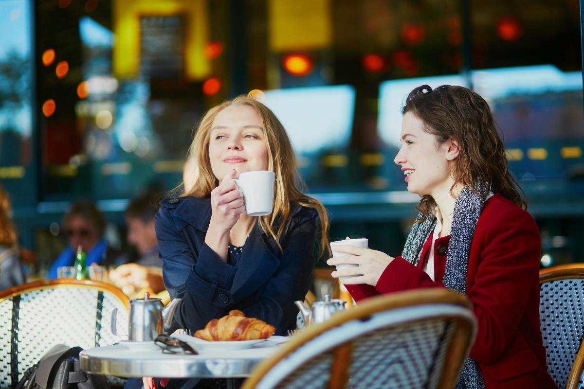 Dos mujeres sentadas en una mesa tomando café