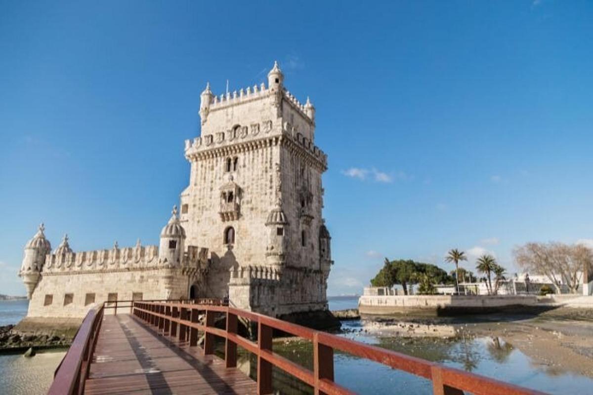 uma torre branca sentada sobre a água ao lado de uma ponte