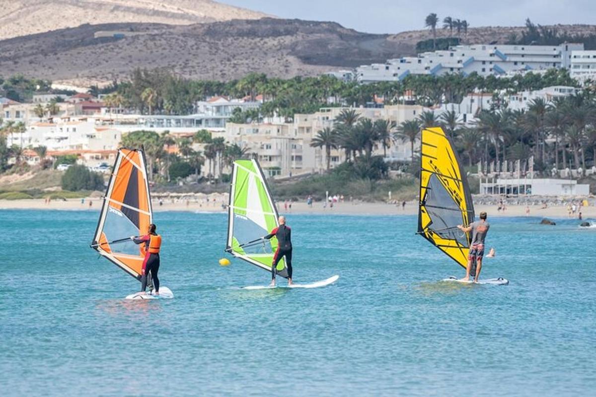 tatlong tao ang windsurfing sa tubig sa dalampasigan