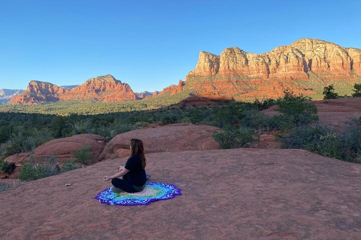 a woman sitting on a rock looking at the mountains