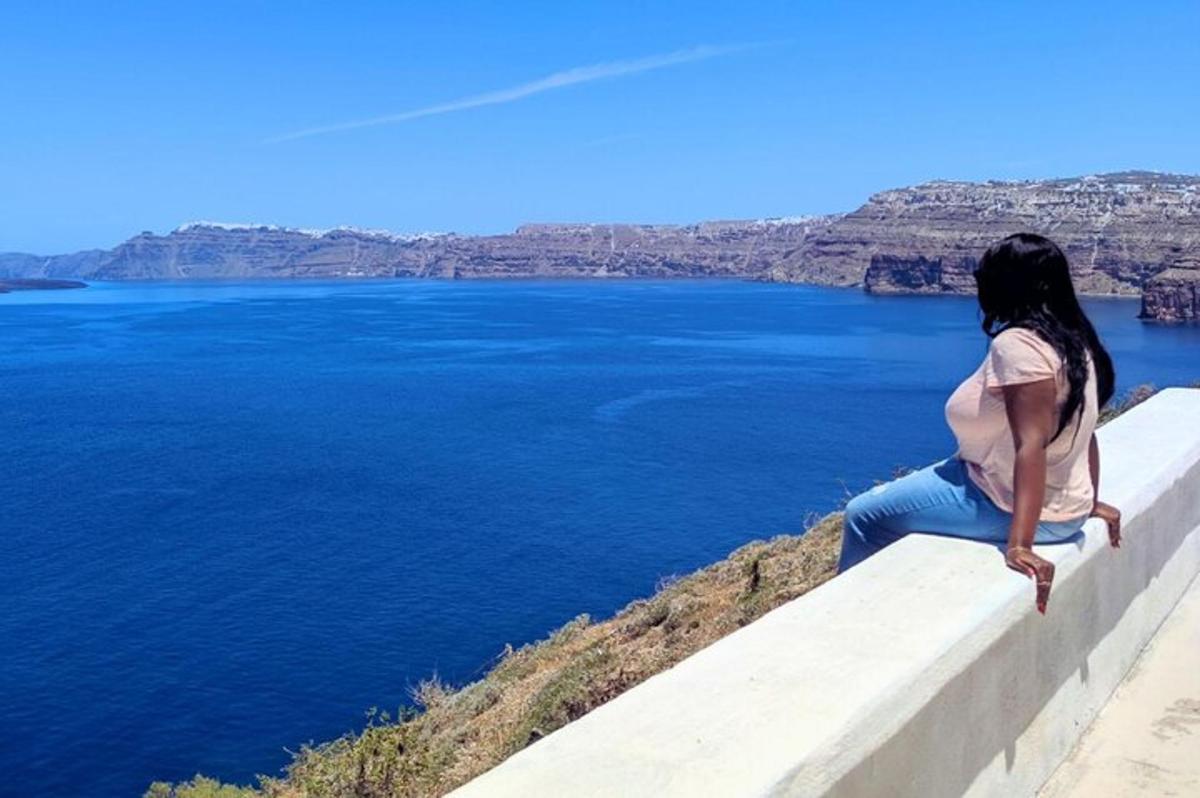 una donna seduta su un muro che guarda l'acqua