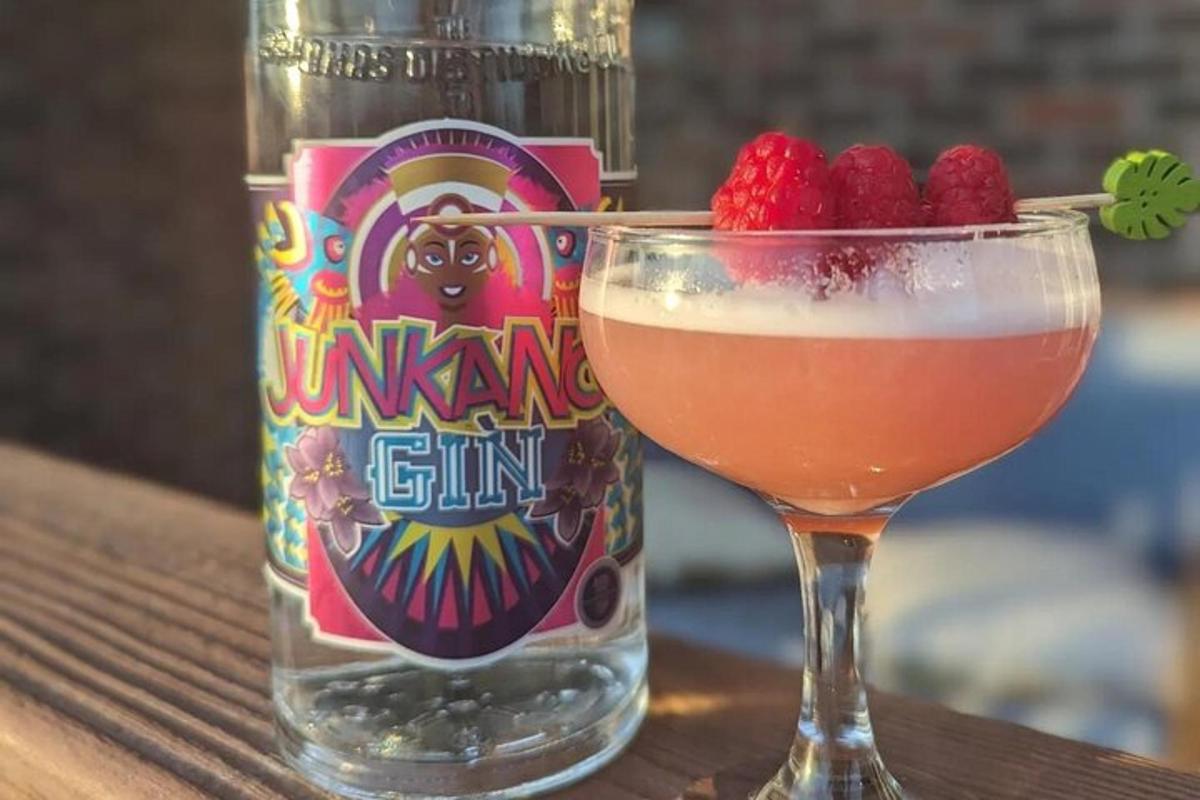 a drink in a glass next to a bottle of gin