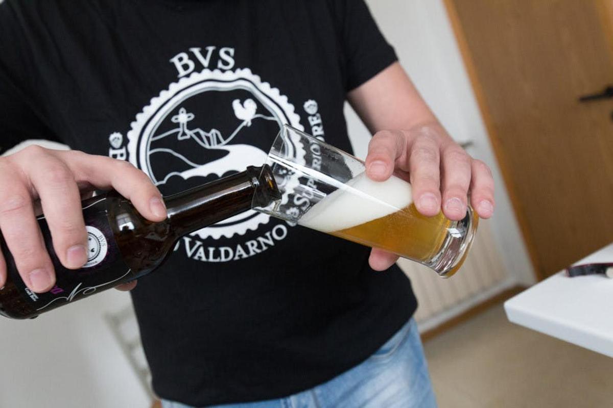 člověk nalévající pivo do sklenice