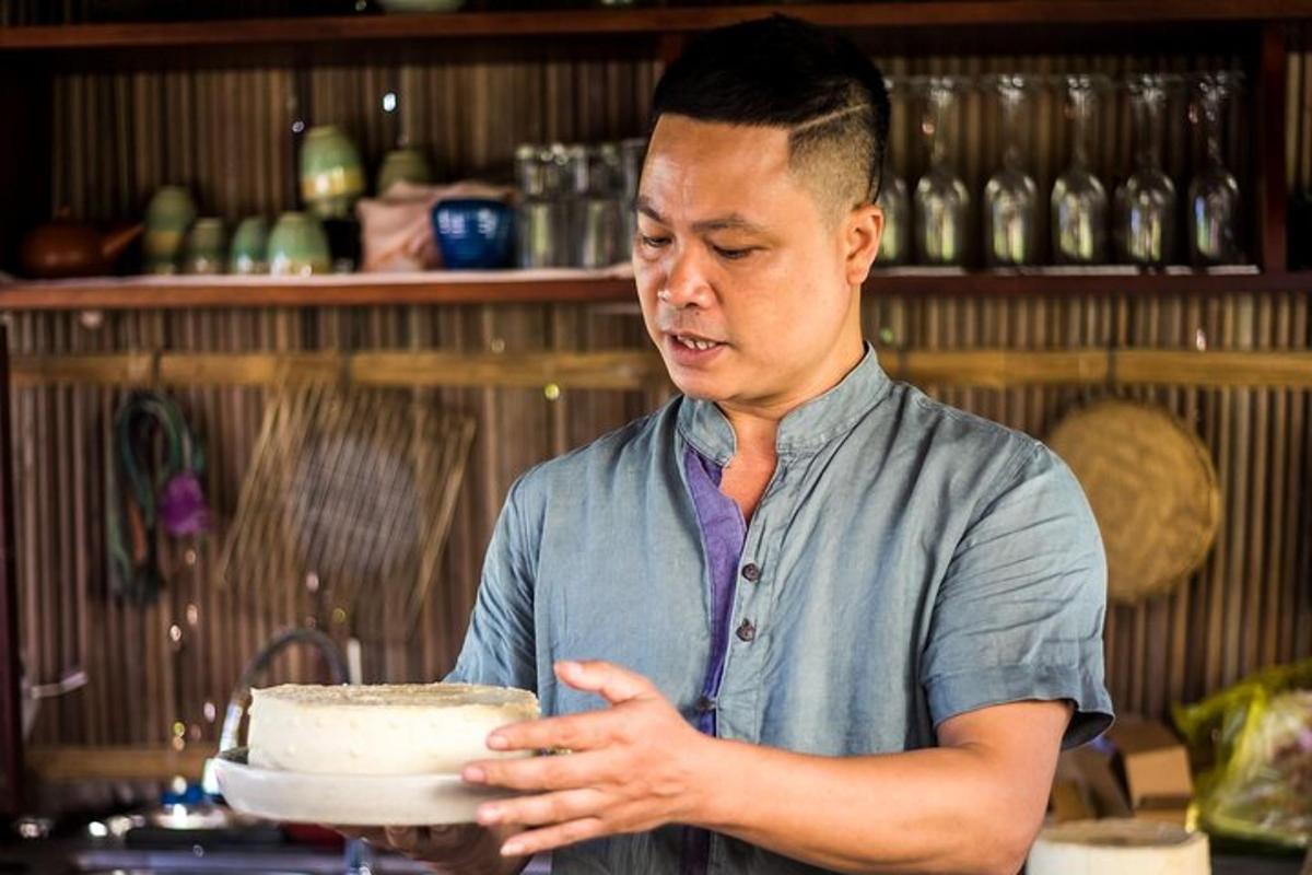một người đàn ông đứng trong bếp cầm một chiếc bánh