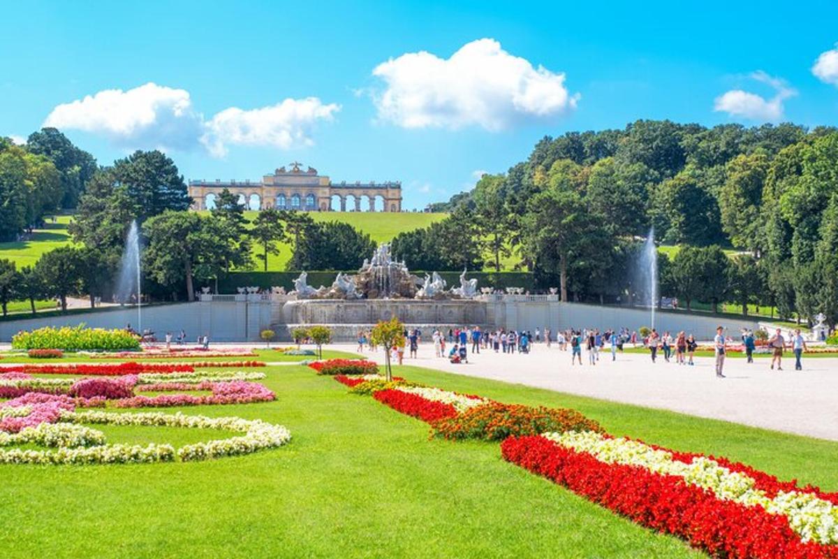 um parque com uma fonte e flores em frente a um prédio