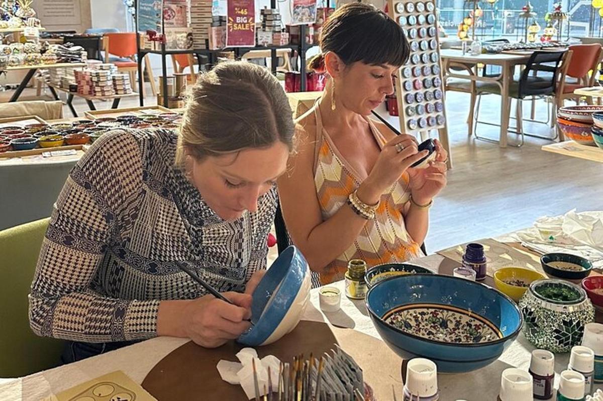 Dos mujeres sentadas en una mesa mirando sus teléfonos móviles.