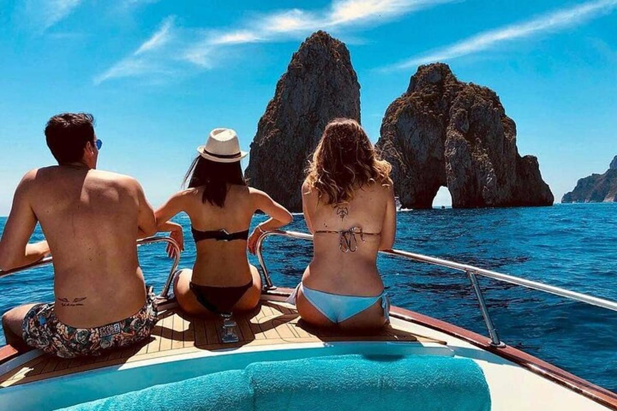tre persone in bikini sedute su una barca nell'oceano