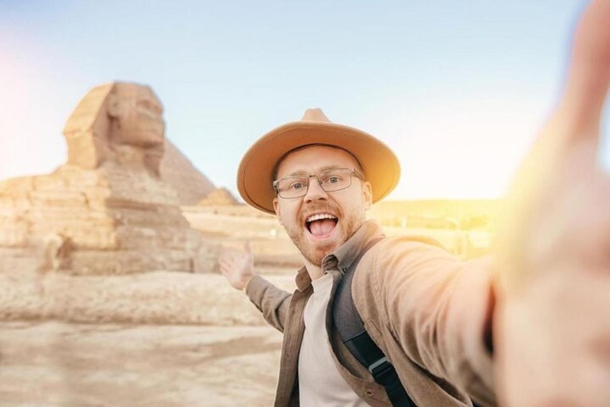 un uomo con un cappello in piedi davanti alle piramidi